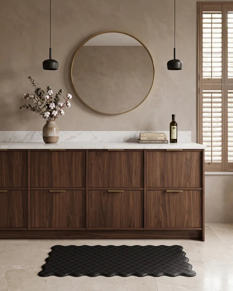 Black scalloped anti-fatigue kitchen mat placed in front of wooden cabinets
