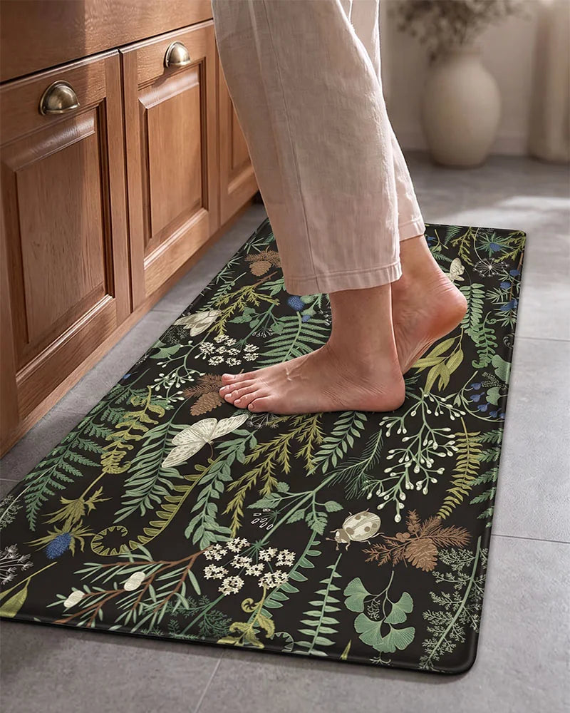 Bare feet standing on an Ink Moss Green cushioned botanical kitchen mat
