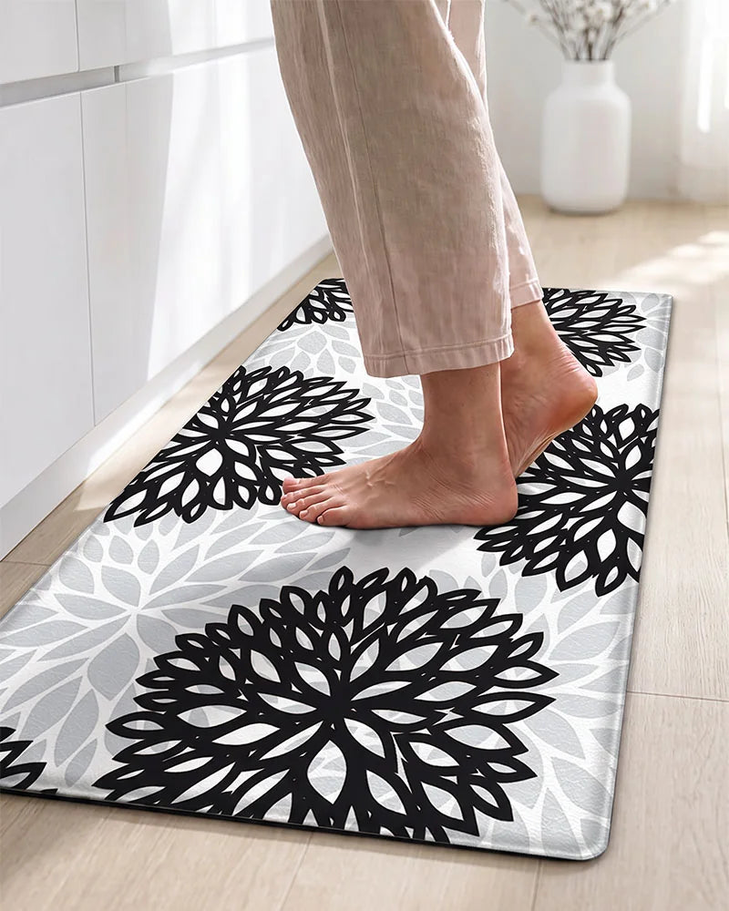 Bare feet on a Black Gray cushioned dahlia floral anti-fatigue kitchen mat