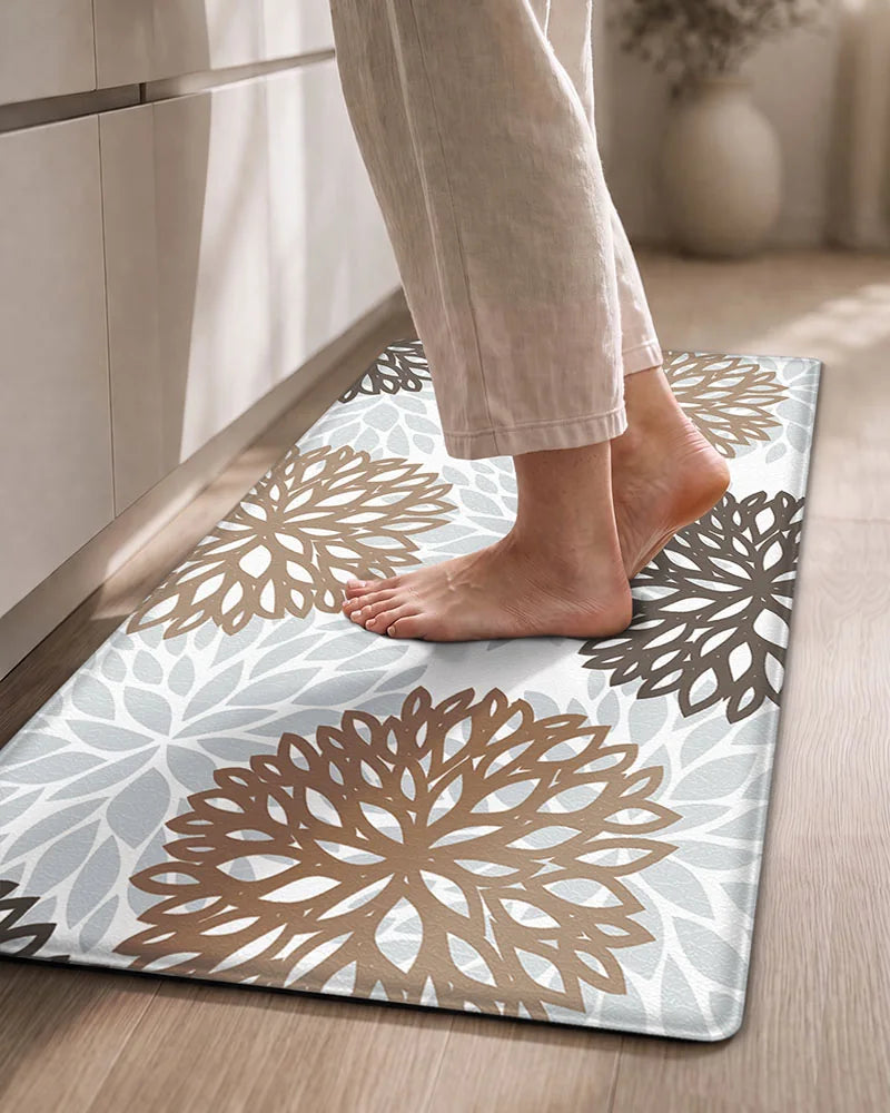 Bare feet on a Brown Grey cushioned dahlia floral anti-fatigue kitchen mat
