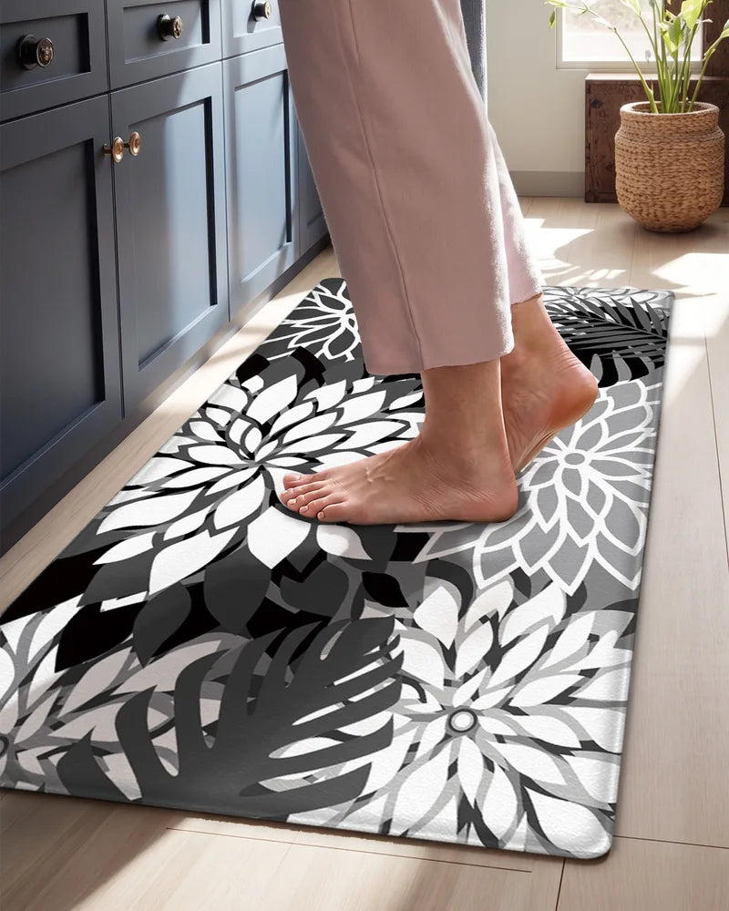 Bare feet standing on a Black White floral cushioned anti-fatigue kitchen mat