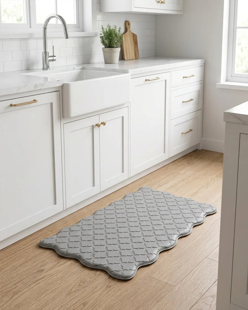 Gray scalloped anti-fatigue kitchen mat in front of white cabinets