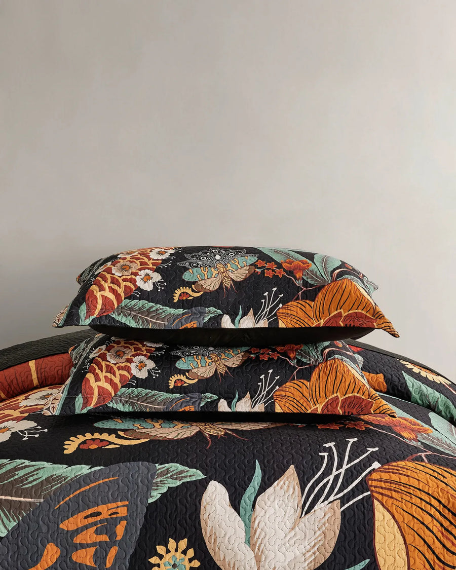 Folded boho floral quilt set featuring the Mocha Noir pattern