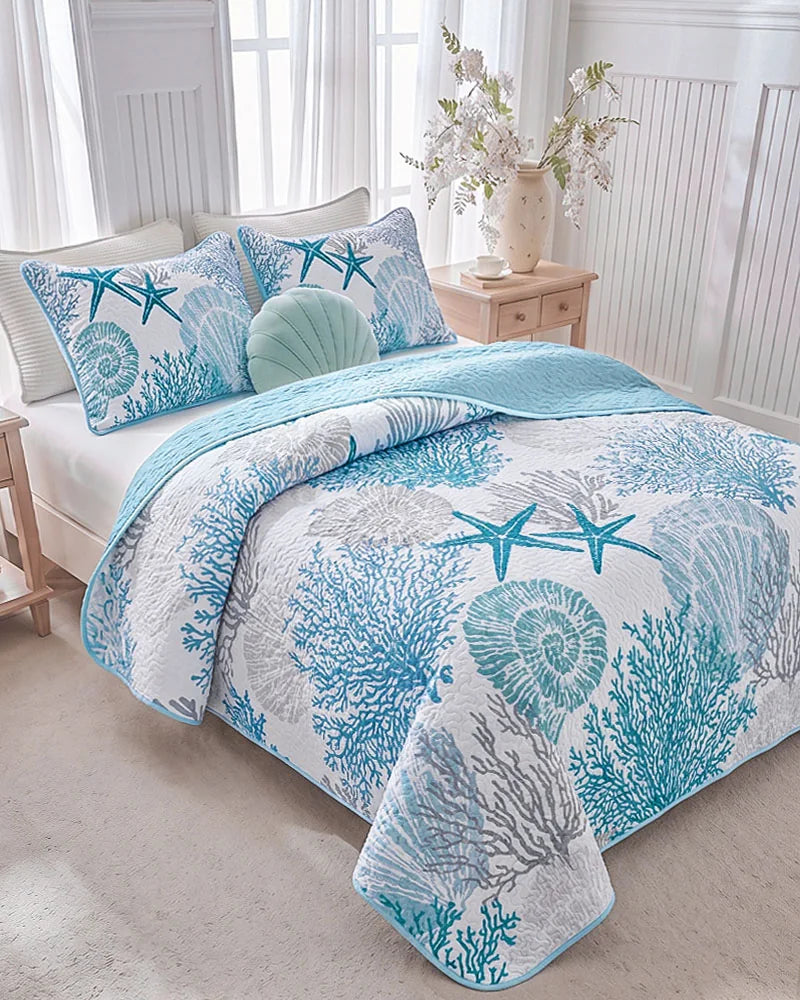 Ocean-themed quilt set with seashell pillow in a sunlit white bedroom