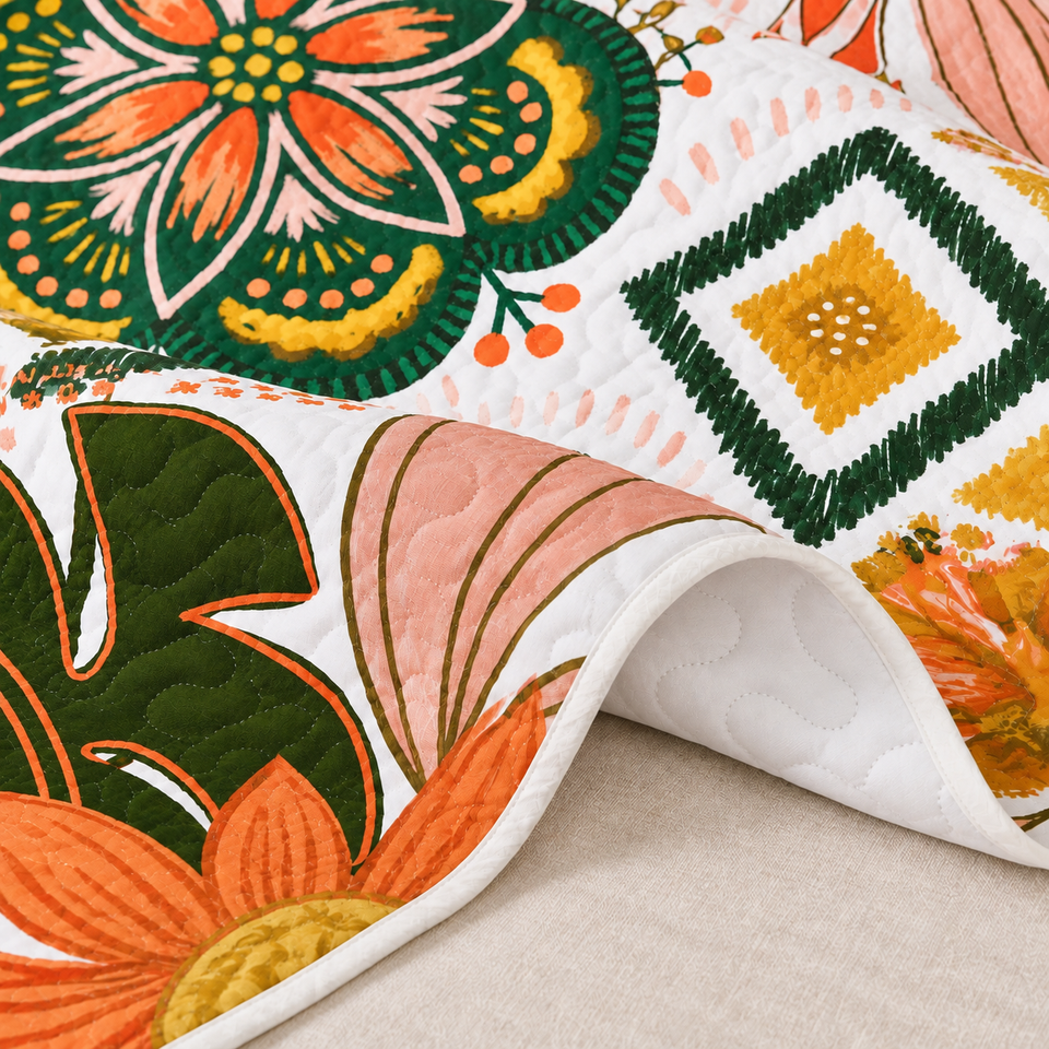 Flore quilt in Blush Pearl folded to show its white reverse, bound edge and orange and green floral front.