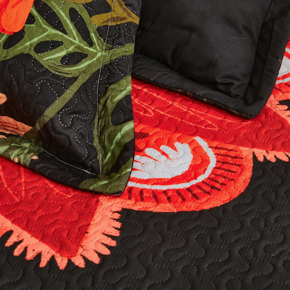 Flore quilt and sham in Crimson Shadow, with red flowers, green leaves and curved quilting on black fabric.