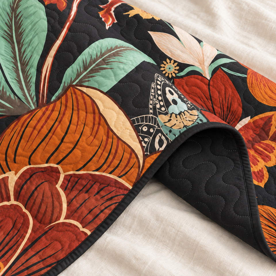 Flore quilt in Mocha Noir folded to reveal its black reverse, bound edge and orange floral print with mint-green leaves.