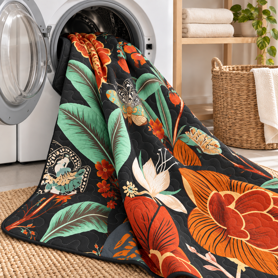 Flore quilt in Mocha Noir draped from an open front-loading washer, showing orange flowers and mint-green leaves.