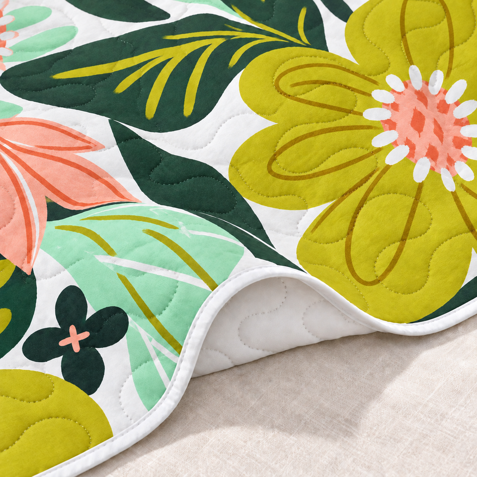 Flore quilt in Rose Garden folded to show its white reverse, bound edge and yellow-green floral front.