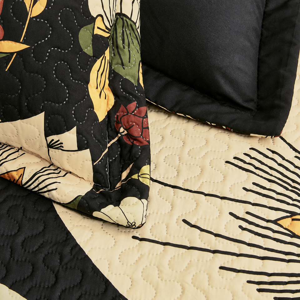 Flore quilt and sham in Warm Ember, showing cream flowers, olive leaves and curved quilting on black fabric.