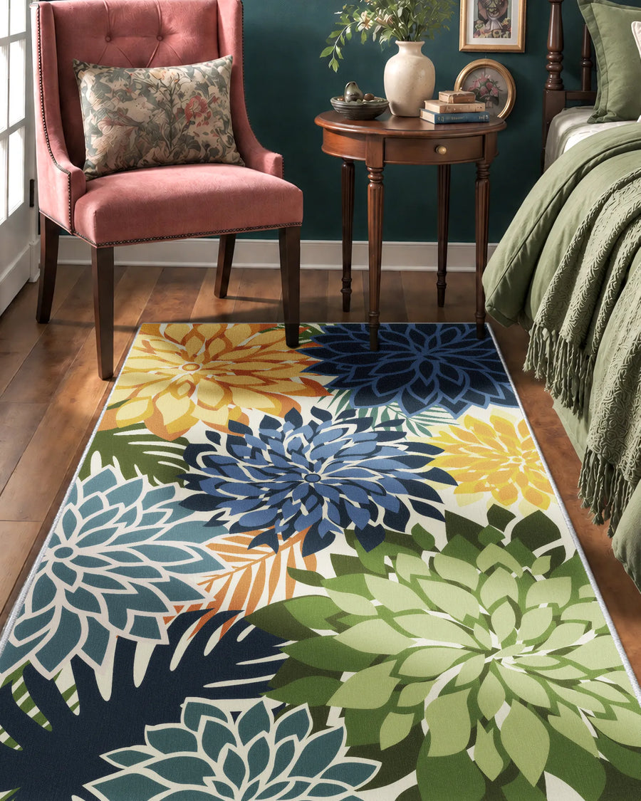 Floral area rug with blue and green dahlias beside a bed and accent chair